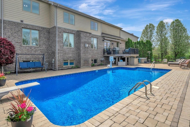 pool featuring a patio, outdoor lounge area, and a diving board