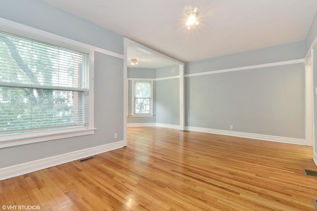 empty room with baseboards, light wood finished floors, and visible vents