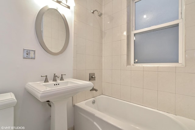 bathroom with toilet,  shower combination, and a sink