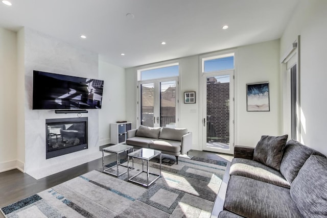 living room featuring baseboards, a fireplace, recessed lighting, and wood finished floors