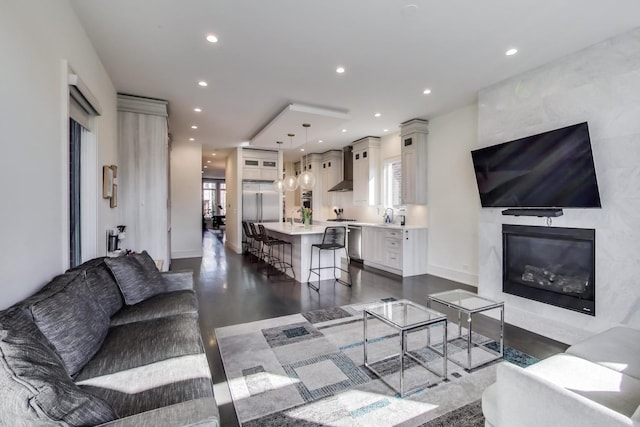 living room featuring recessed lighting, dark wood-style floors, and a high end fireplace