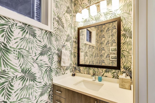 half bathroom featuring vanity and wallpapered walls