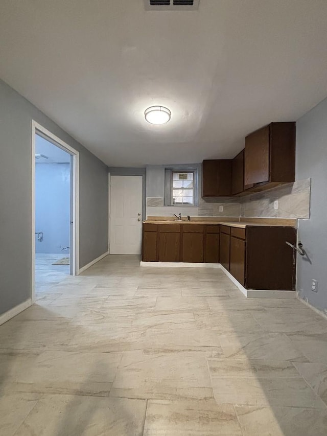 kitchen featuring baseboards, dark brown cabinetry, and light countertops