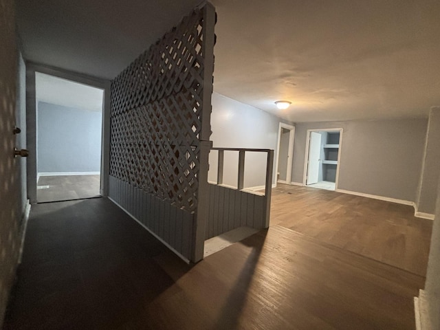 hallway with an upstairs landing, wood finished floors, and baseboards