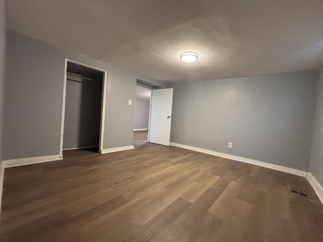 unfurnished bedroom featuring visible vents, a closet, dark wood finished floors, and baseboards