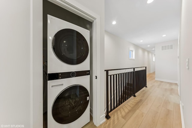 laundry area featuring laundry area, visible vents, stacked washer / drying machine, wood finished floors, and recessed lighting