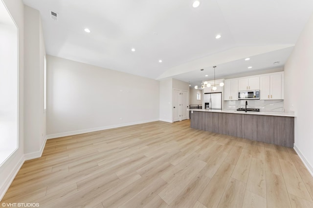 kitchen with appliances with stainless steel finishes, light countertops, recessed lighting, light wood-type flooring, and visible vents