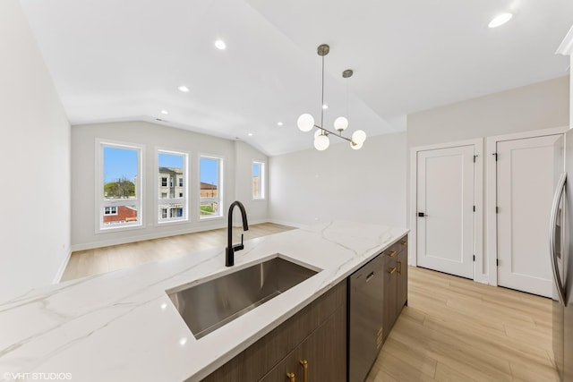 kitchen featuring pendant lighting, appliances with stainless steel finishes, vaulted ceiling, a sink, and light wood-style floors