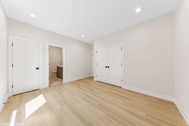 unfurnished bedroom featuring baseboards, recessed lighting, light wood-style flooring, and ensuite bathroom