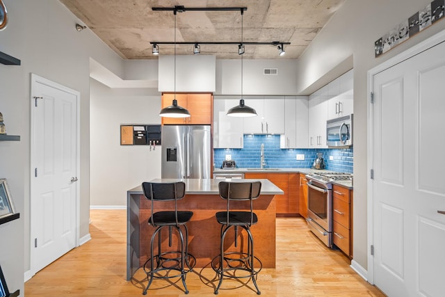 kitchen with a sink, stainless steel appliances, rail lighting, and light wood-style flooring