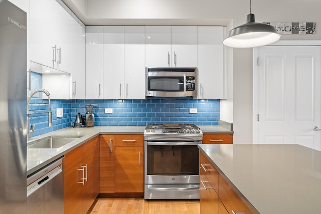 kitchen featuring brown cabinetry, modern cabinets, white cabinets, a sink, and stainless steel appliances