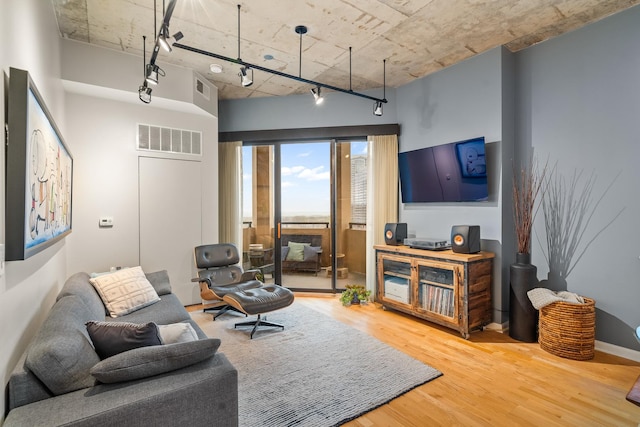 living area with track lighting, wood finished floors, and visible vents