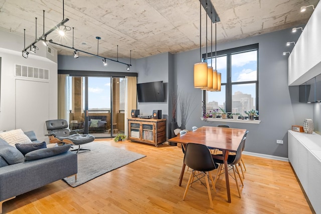 dining area featuring baseboards, visible vents, track lighting, and wood finished floors