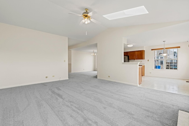 14 Mckinley Ln, Streamwood, IL 60107 - unfurnished living room featuring vaulted ceiling with skylight, baseboards, ceiling fan with notable chandelier, and light colored carpet