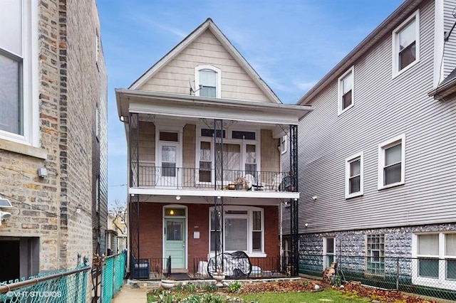 view of front of property with a balcony, fence private yard, covered porch, and brick siding