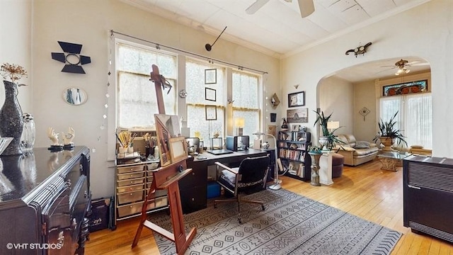 office space with crown molding, a ceiling fan, arched walkways, and wood-type flooring
