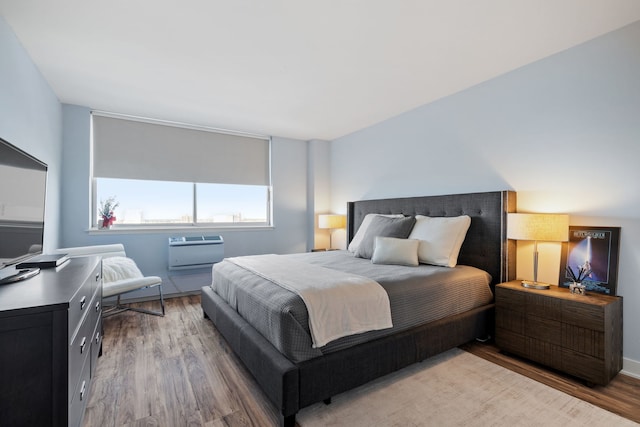 bedroom with an AC wall unit and wood finished floors