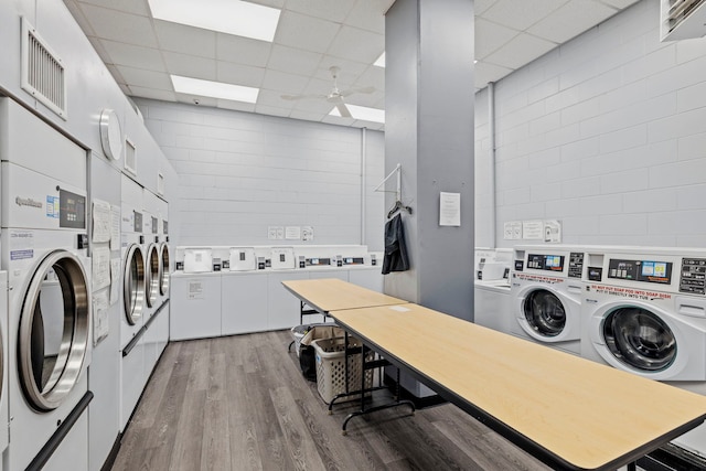 common laundry area with ceiling fan, visible vents, washing machine and dryer, stacked washing maching and dryer, and light wood finished floors
