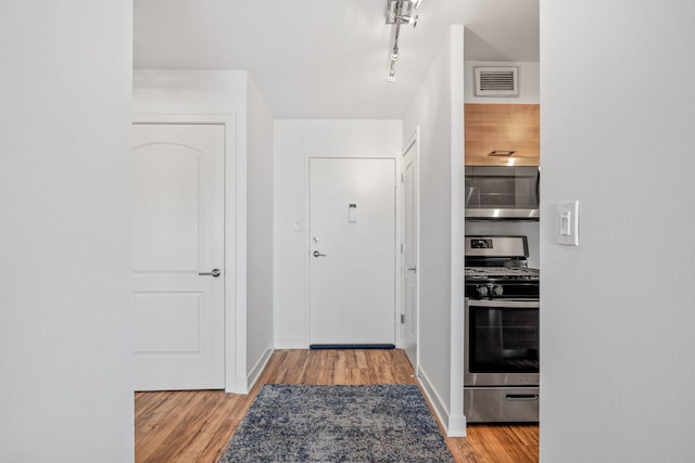 foyer entrance with visible vents, baseboards, wood finished floors, and track lighting
