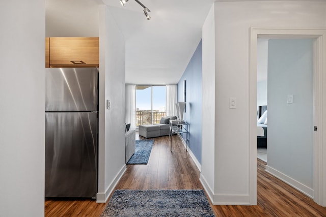 corridor featuring baseboards, track lighting, and wood finished floors