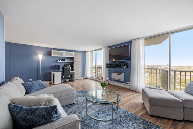 living area with floor to ceiling windows, a wall unit AC, and wood finished floors