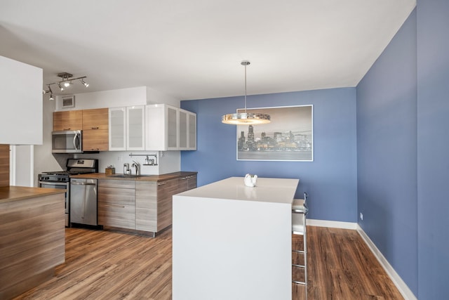 kitchen with stainless steel appliances, visible vents, modern cabinets, and dark wood-type flooring