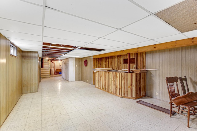 bar with stairway, light floors, wood walls, and a paneled ceiling