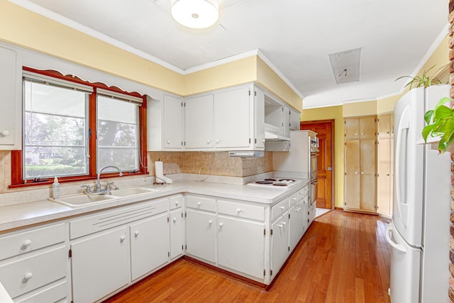 kitchen featuring a sink, light wood-style flooring, white appliances, and light countertops