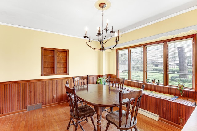 dining area with visible vents, light wood-style flooring, a wainscoted wall, and a chandelier