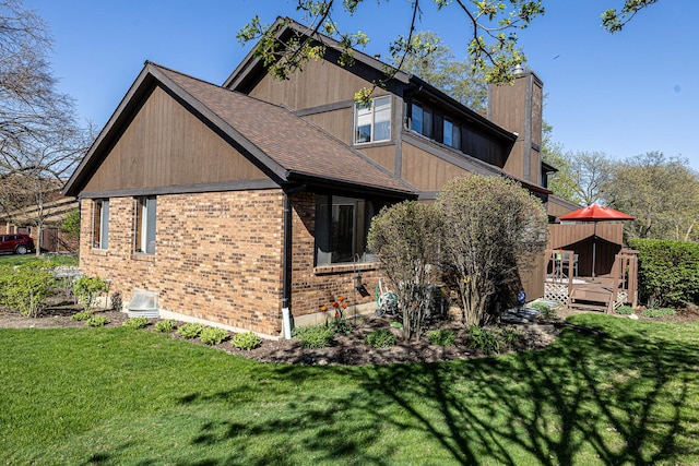 view of home's exterior featuring a lawn, brick siding, a chimney, and a deck