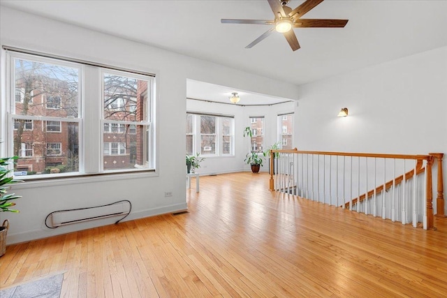 spare room featuring ceiling fan, baseboards, plenty of natural light, and hardwood / wood-style floors