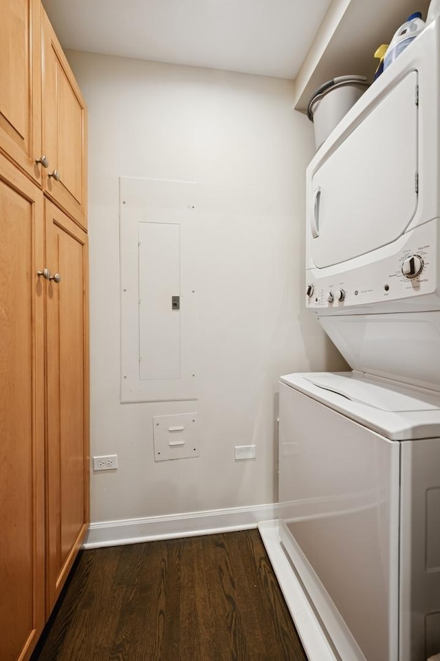 laundry room with baseboards, stacked washing maching and dryer, dark wood-style floors, electric panel, and cabinet space