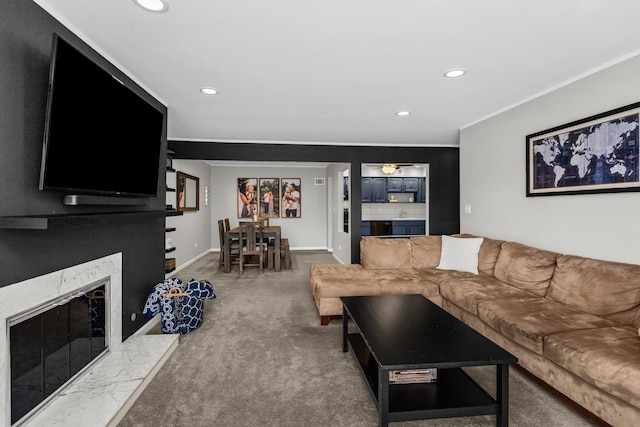 carpeted living area with recessed lighting, baseboards, ornamental molding, and a high end fireplace