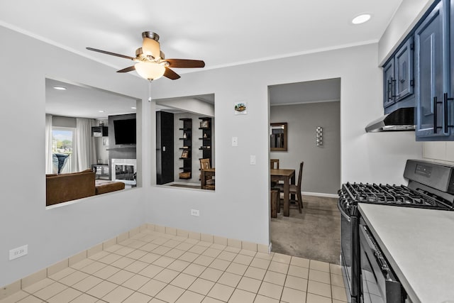 kitchen featuring gas range oven, light countertops, under cabinet range hood, blue cabinets, and a ceiling fan