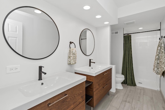 bathroom featuring visible vents, a stall shower, two vanities, a sink, and recessed lighting