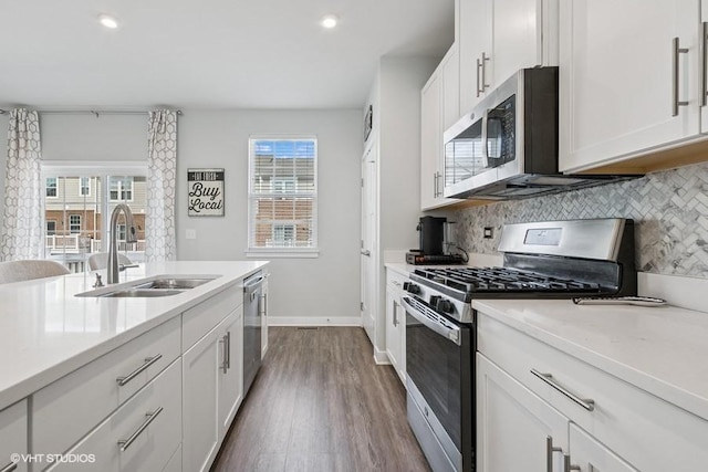 kitchen featuring a sink, dark wood finished floors, appliances with stainless steel finishes, and tasteful backsplash