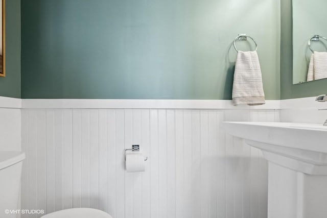 half bathroom with a wainscoted wall and toilet