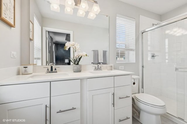 full bath with a sink, a shower stall, toilet, and double vanity