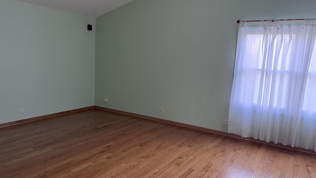 empty room featuring baseboards, visible vents, and light wood finished floors