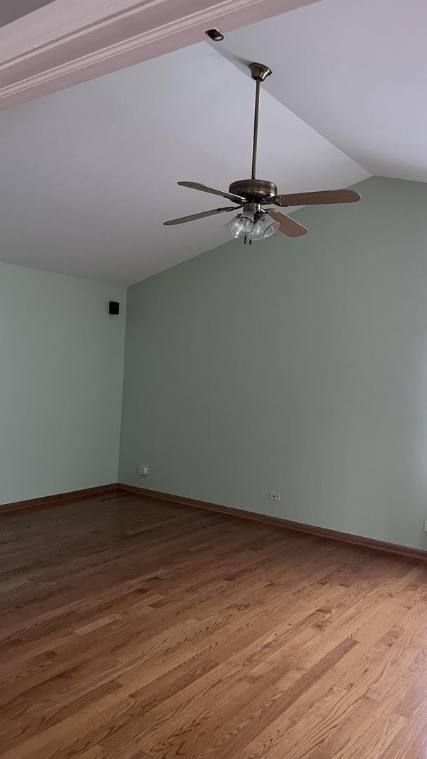unfurnished room with baseboards, a ceiling fan, vaulted ceiling, and wood finished floors