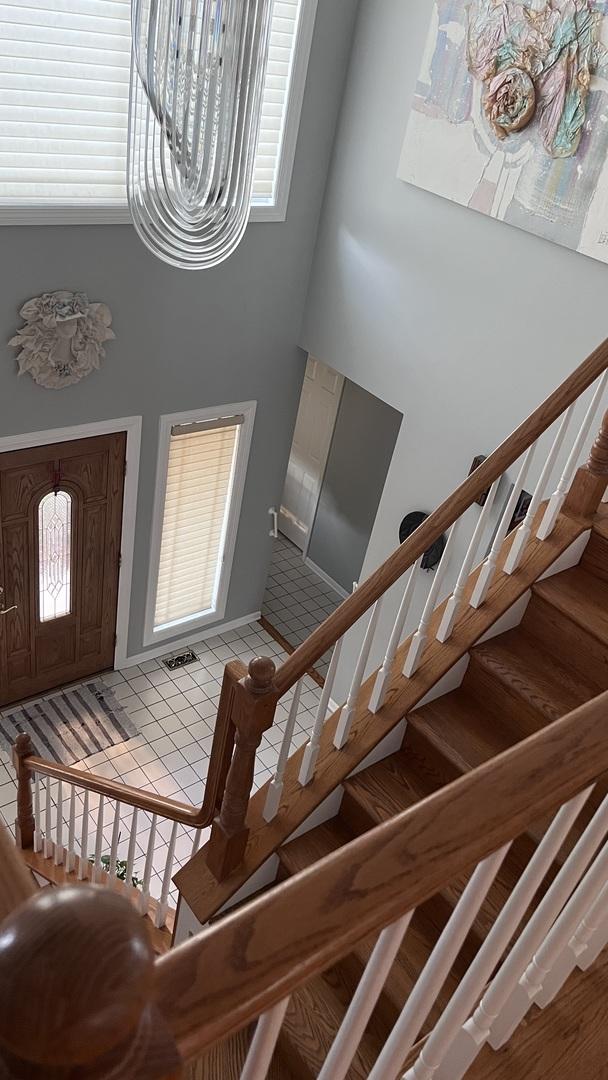 entryway with light tile patterned flooring, a high ceiling, and stairway