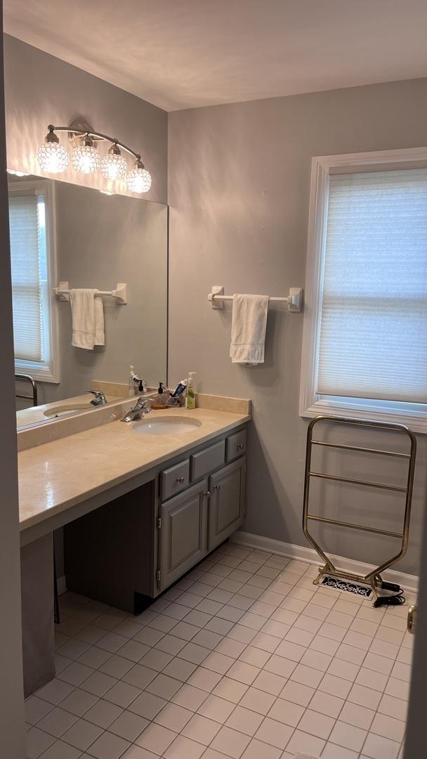 bathroom featuring baseboards, tile patterned floors, a healthy amount of sunlight, and vanity