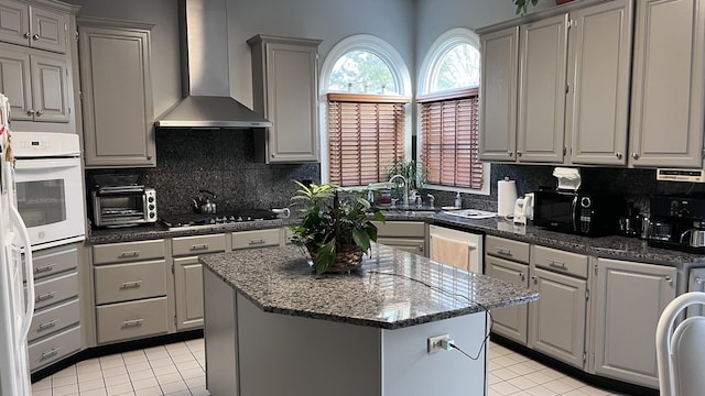 kitchen featuring a toaster, white appliances, gray cabinets, wall chimney exhaust hood, and light tile patterned floors