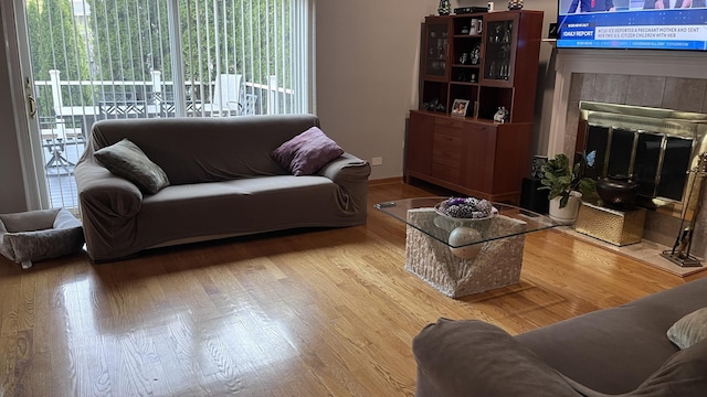 living room featuring a tiled fireplace and wood finished floors
