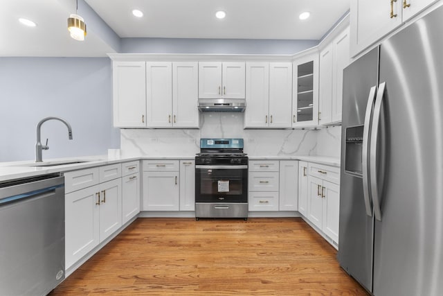 kitchen with appliances with stainless steel finishes, a sink, white cabinets, and under cabinet range hood