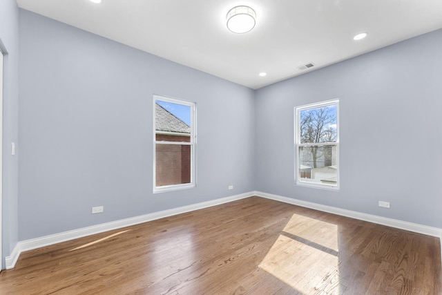 unfurnished room featuring wood finished floors, visible vents, recessed lighting, and baseboards