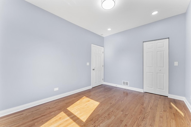 spare room featuring recessed lighting, visible vents, wood finished floors, and baseboards