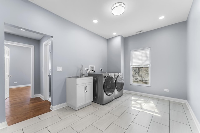 laundry room featuring baseboards, cabinet space, separate washer and dryer, and a sink