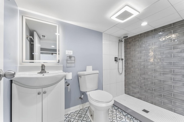bathroom featuring visible vents, tiled shower, toilet, and vanity
