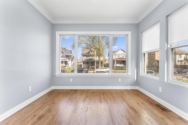 unfurnished room featuring ornamental molding, visible vents, wood finished floors, and baseboards